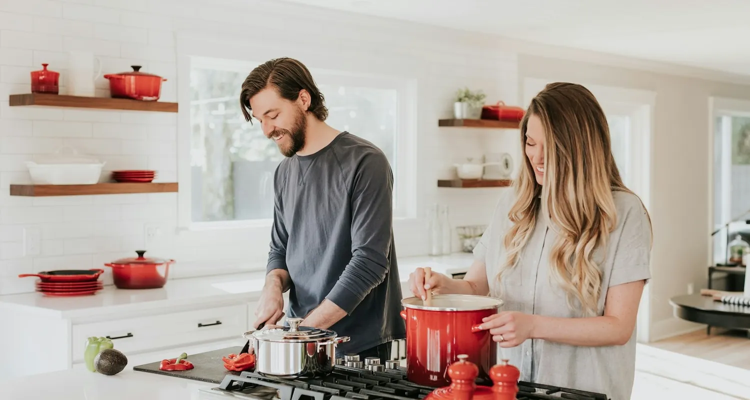 Couple preparing food in their kitchen, smiling and laughing
